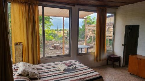 Schlafzimmer mit einem Bett und großen Fenstern in der Unterkunft Casita entre dunas al son del mar in Salinas