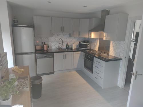 a kitchen with white cabinets and white appliances at Lewis Square Town House in Belfast