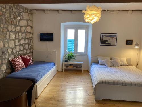 two beds in a room with a brick wall at Apartment Naval in Dubrovnik