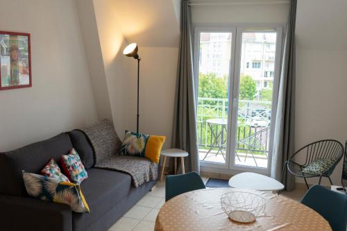 uma sala de estar com um sofá e uma mesa em 2 pièces Port Cabourg - 2 à 4 personnes - 34 m2 - Balcon - Vue Port - Nouveau sur Booking ! em Dives-sur-Mer