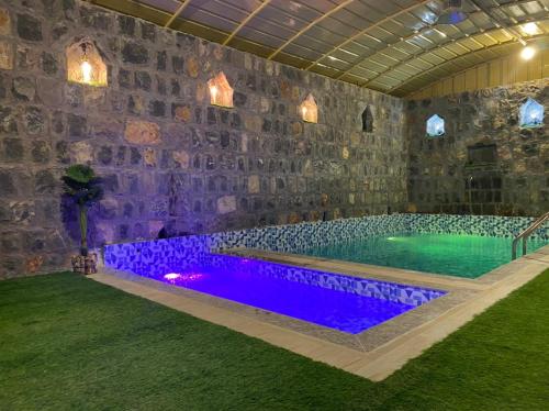 einen Pool in einem Zimmer mit einer Steinmauer in der Unterkunft alreaambreather2 in Sayq