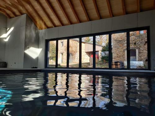 ein leerer Pool mit einem großen Fenster und einem Gebäude in der Unterkunft Gîte avec piscine intérieure in Moyrazès