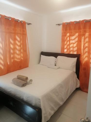 Cama en habitación con 2 cortinas de color naranja en Residencial sarah de los Angeles, en SJM