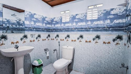 a bathroom with a toilet and a sink with a beach mural at Sun Set Sea Family House in Weligama