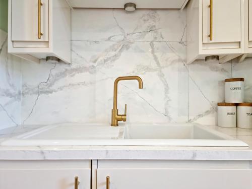 a white kitchen with a sink and gold faucet at Unique Victorian Home in Glasgow in Glasgow