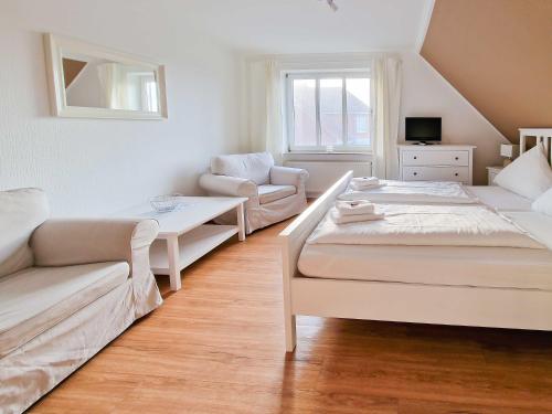 a white room with two beds and a couch at Gästehaus Funk in Greetsiel