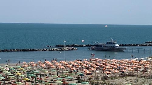 un gran grupo de sombrillas en una playa con un barco en Hotel Rosati, en Rímini