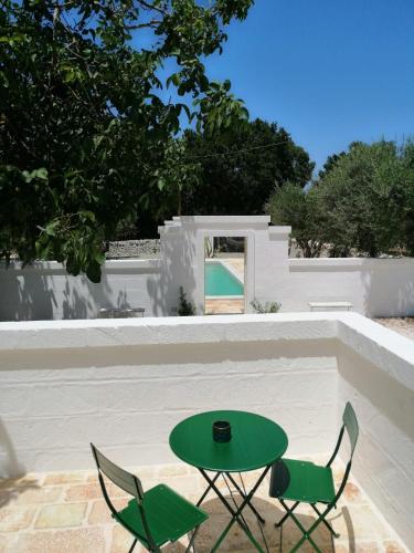 a green table and chairs in front of a white wall at Intornoalnoce in Cisternino