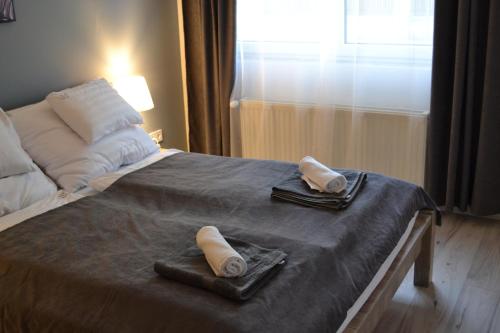 a bed with two towels on top of it at Főnix Design Rooms in Debrecen