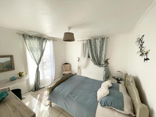 a bedroom with a bed in a room with windows at Ti Kaz Vacoas in Saint-Louis