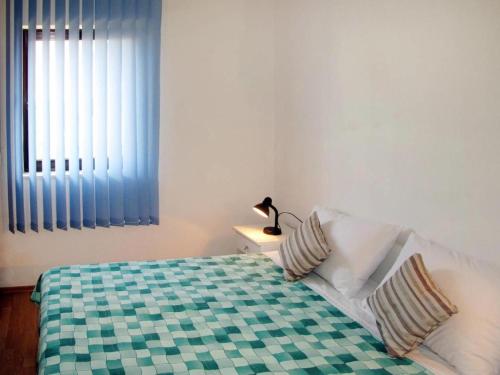 a bedroom with a bed with a checkered blanket and a window at Joso Dalmatia in Vir