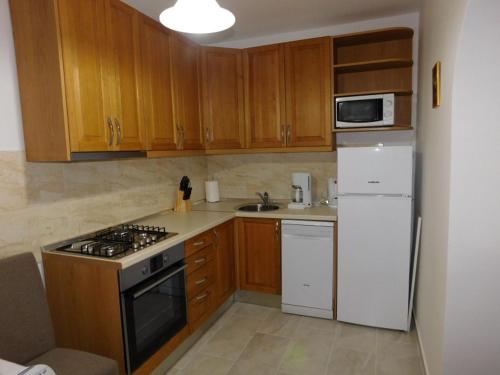 a kitchen with wooden cabinets and a white refrigerator at Apartman Braja in Virovitica