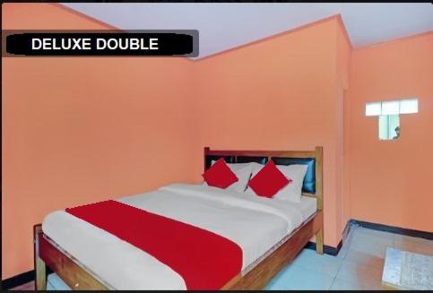 a bedroom with a bed with red and white pillows at Adinda Homestay Lembang in Lembang
