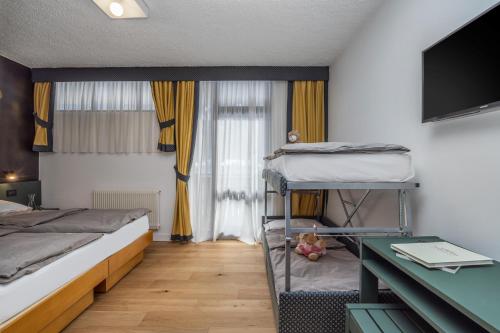 a bedroom with two bunk beds and a desk at Pippo Hotel in Terzolas