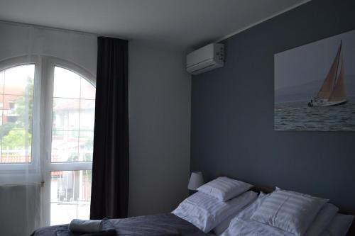 a bedroom with a bed and a window with a sailboat at Főnix Design Rooms in Debrecen