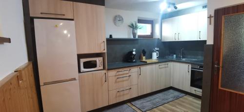 a kitchen with wooden cabinets and a white refrigerator at Vilka Stefi in Ždiar