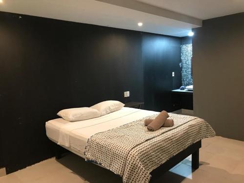 una camera con un letto con una parete nera di Veleta Inn a Tulum
