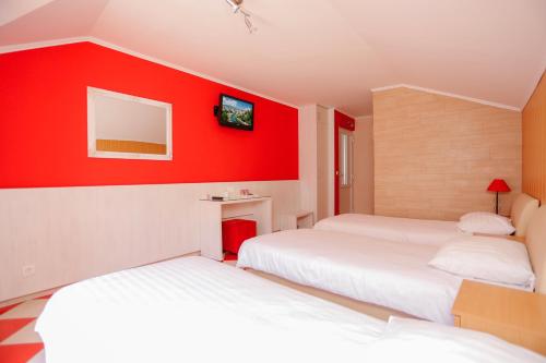 two beds in a room with red walls at Hotel - Villa Lejla in Mostar