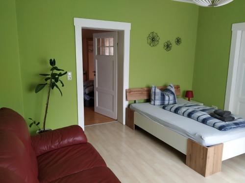 1 dormitorio con cama, sofá y paredes verdes en Ferienwohnung Familie Bulst en Naumburg (Saale)