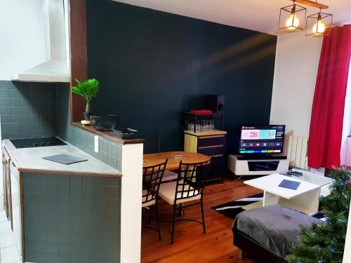 a kitchen and dining room with a table and a television at La ruelle des 2 vallées in Arreau