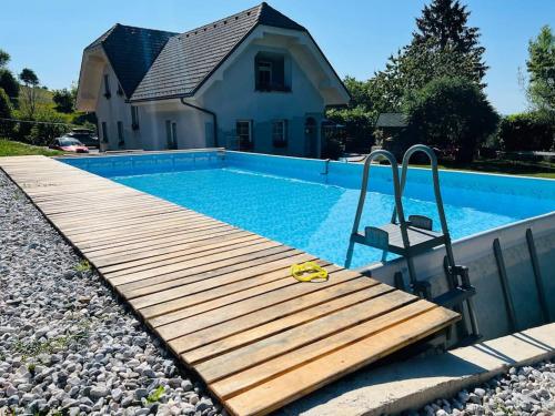 a swimming pool with a wooden deck next to a house at Apartment Sofia in Idrija