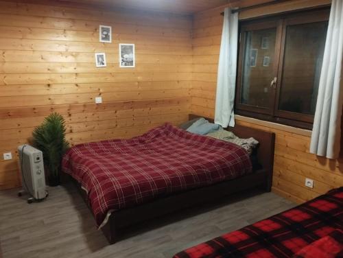 sypialnia z łóżkiem w drewnianej ścianie w obiekcie Châlet 8 personnes + grand terrain et rivière w mieście Entremont