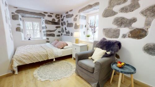 1 dormitorio pequeño con 1 cama y 1 silla en Romantická chalupa s krbem, en Hořice na Šumavě
