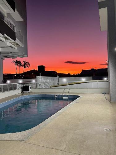 una piscina con puesta de sol en el fondo en Belissimo apto Ingleses, en Florianópolis