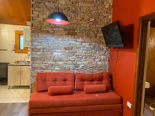 un divano rosso seduto di fronte a un muro di mattoni di Bungalow Rio Olivia a Ushuaia