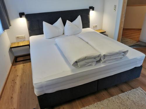 a large bed with white sheets and pillows on it at Bella Vista Apartments in Nauders