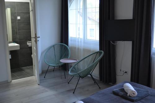 2 sillas y una mesa en una habitación con ducha en Főnix Design Rooms, en Debrecen