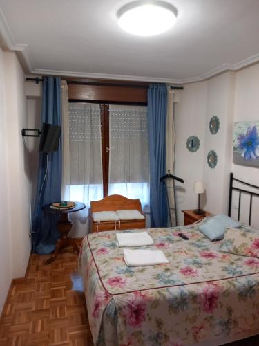 1 dormitorio con 1 cama, 1 silla y 1 ventana en Apartamento Los Fresnos, en Gijón