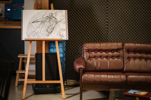 a drawing on a stand next to a brown leather couch at Atelier Recreation Village in Râşnov