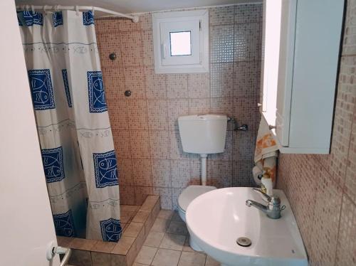 een badkamer met een wastafel, een toilet en een raam bij Asprovalta Beach Apartment in Asprovalta
