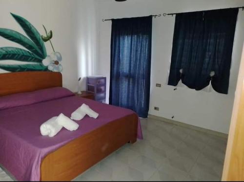a bedroom with a purple bed with towels on it at B&B Romy House in Pianopoli