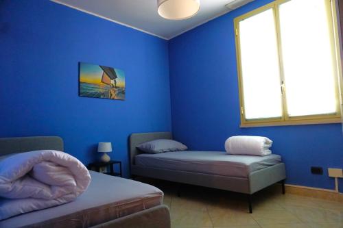 um quarto azul com duas camas e uma janela em IL FIOCCO em Marina di Ravenna