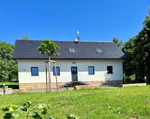 een wit huis met een zwart dak in een veld bij Ubytování pod Troskami in Rovensko pod Troskami