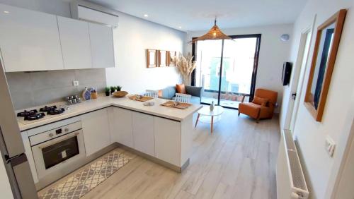 a kitchen with white cabinets and a living room at Ideal Appart la Marsa Jade Résidence de Luxe in La Marsa