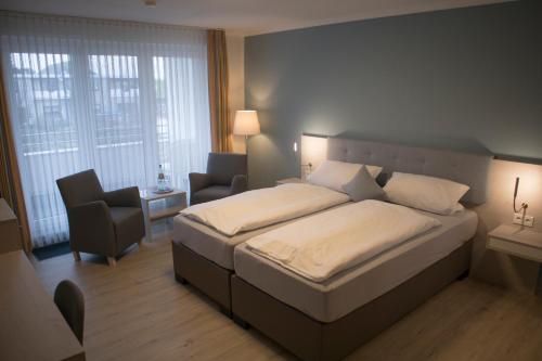 1 dormitorio con 1 cama grande y 1 silla en Hotel Am Friesenstrand, en Butjadingen