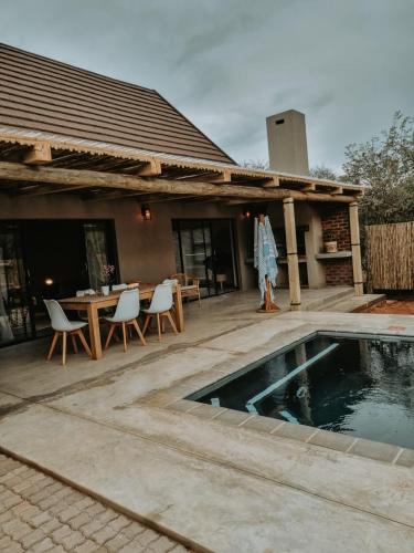 un patio con una mesa y una piscina en UmnDeni Africa, en Hoedspruit