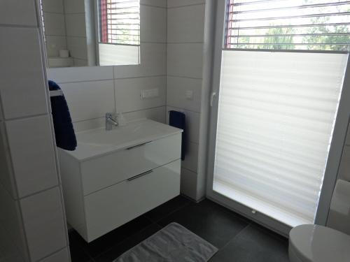 a white bathroom with a sink and a mirror at Lagrette Ferienwohnung am Hainer See in Neukieritzsch