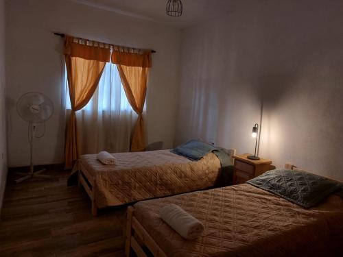 a bedroom with two beds and a window with a fan at Vivienda en Cuchi Corral in Los Puquios