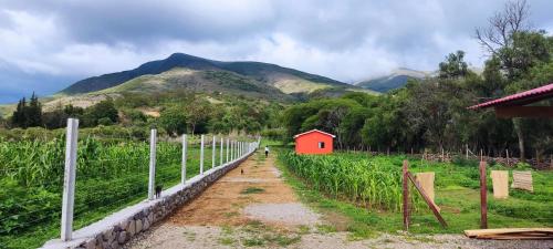 a red barn in a field with mountains in the background at Armonia - La Victoria - Tarija in Tarija