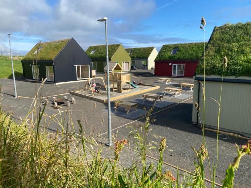 a parking lot with houses and a playground at Luxury Cottage in Serene Nature - Okkara summarhús á Sandi in Sandur