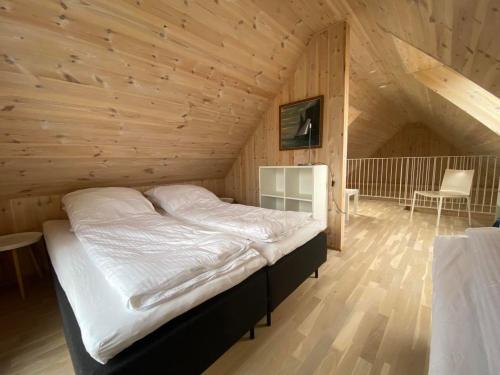 a bedroom with a bed in a wooden room at Okkara summarhús á Sandi - Luxury cottage - Unique location in Sandur