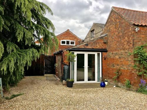 una casa de ladrillo con una puerta blanca y un patio en Ivy House Barn, Heckington, en Heckington