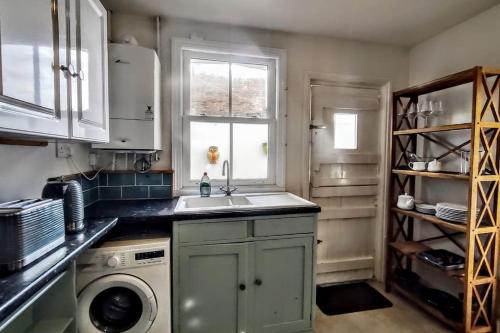 a kitchen with a sink and a washing machine at Cute Cottage 5 min walk from Cafés Station and Sea in Hastings