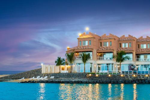 a large building on the shore of the water at Indium Al Fayroz Chalets Durrat AlArus for families only in Durat Alarous