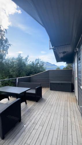 terraza de madera con mesas y sillas en el balcón en Strandbu Camping, en Skibotn