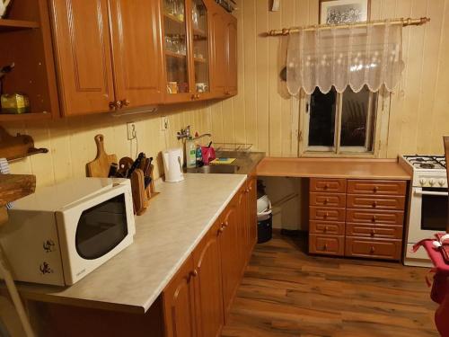 a kitchen with wooden cabinets and a microwave on a counter at Chata Božena - Čertovica in Jarabá